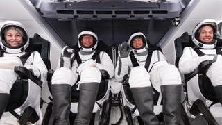 four people in white space suits in a white spaceship